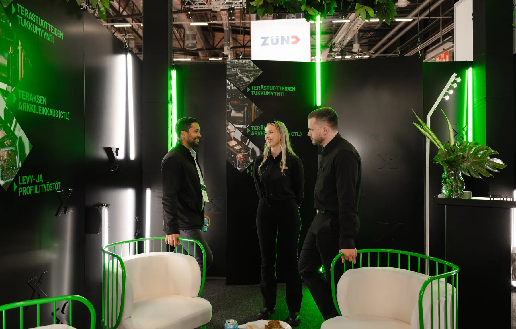 Three people talking in front of the processing service wall