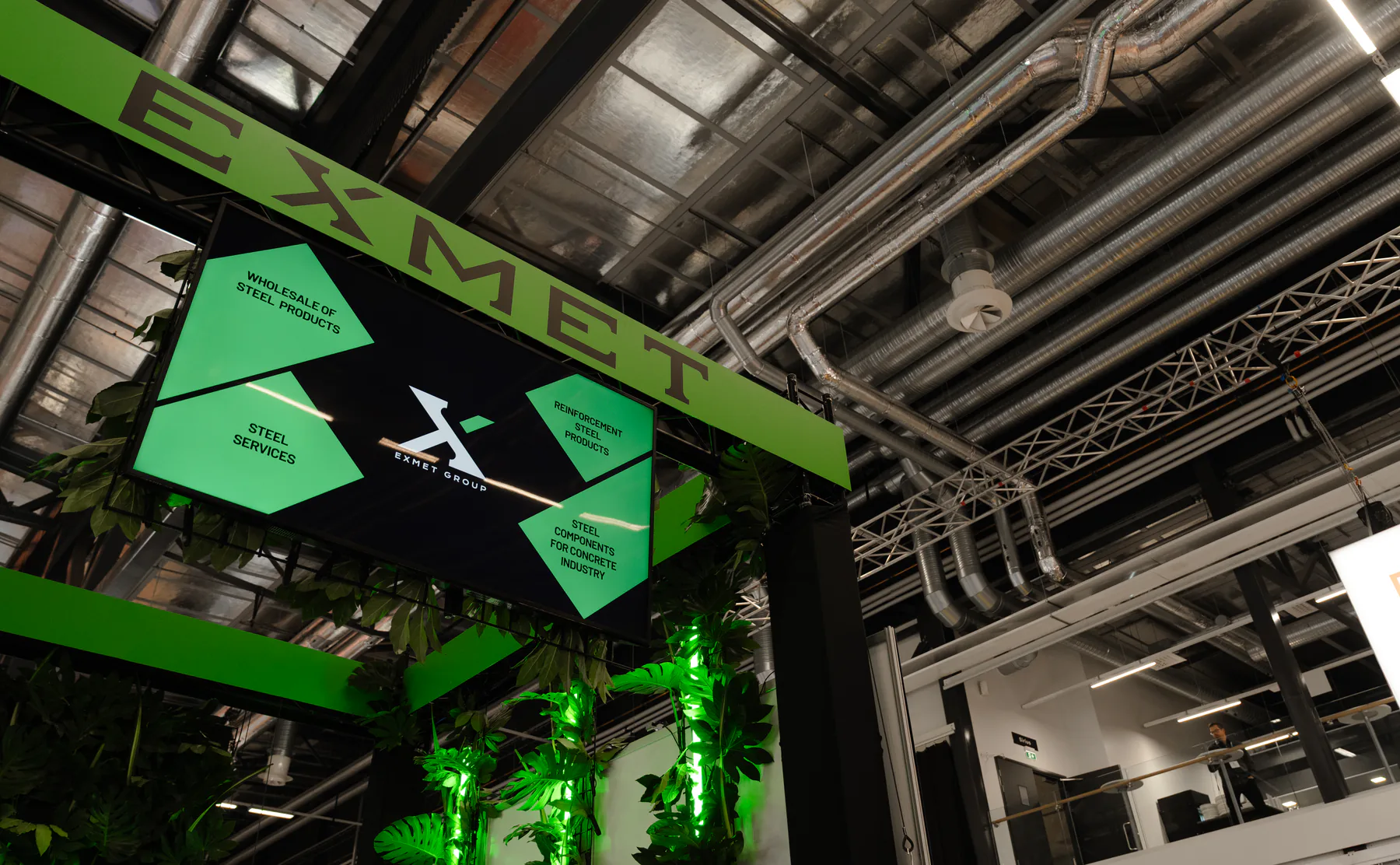 EXMET sign and screen above the stand, seen from below
