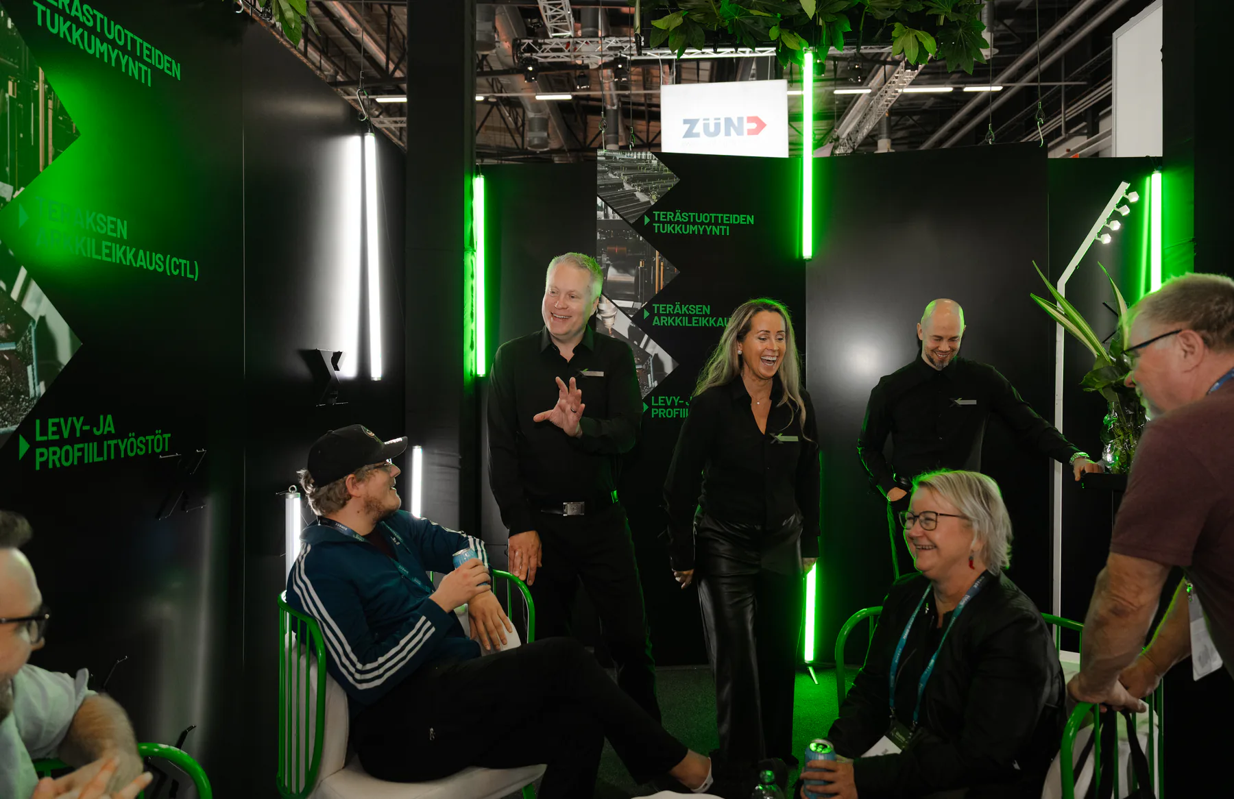 Visitors seated in green chairs talking with the Exmet team