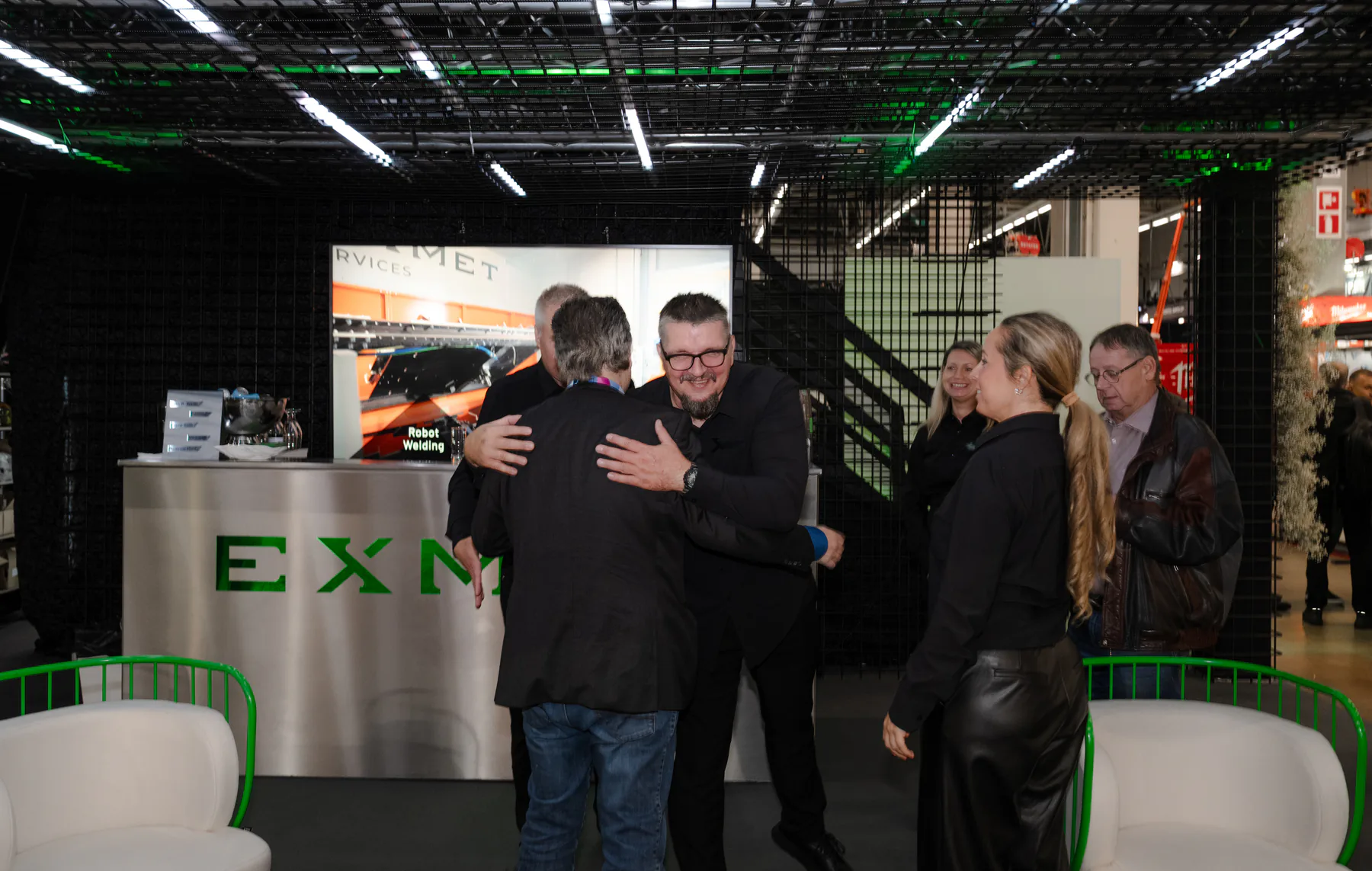Two people hugging in front of the Exmet counter