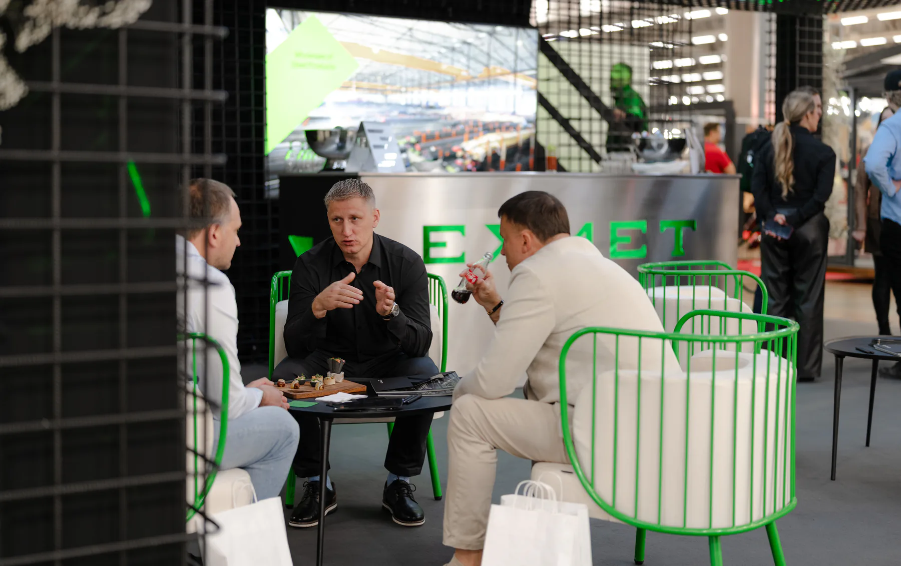 Visitors and an Exmet expert talking in the green lounge chairs