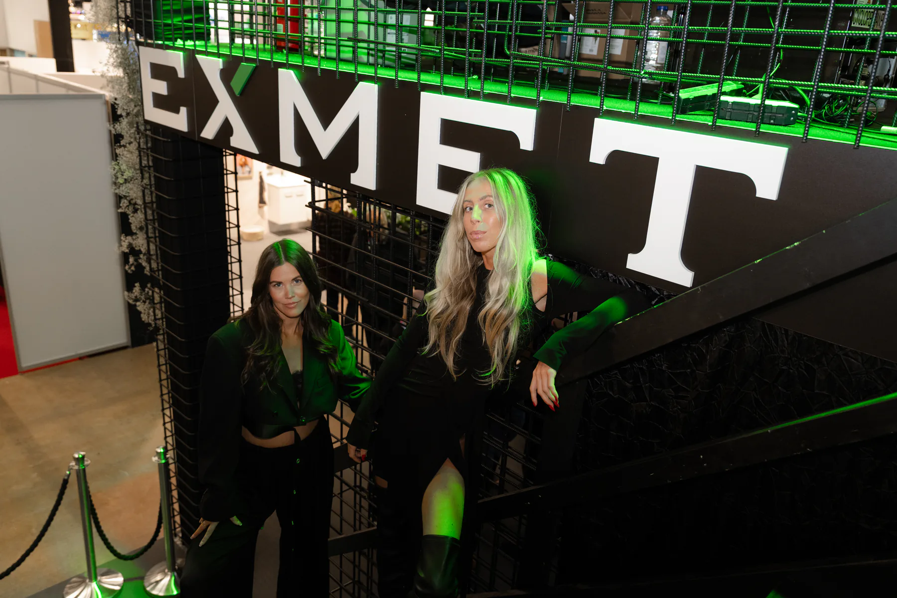 Two guests on the stairs under the EXMET sign
