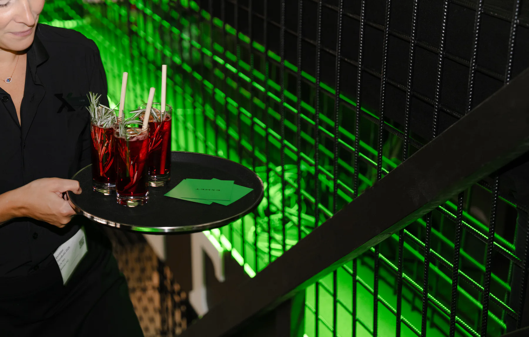 Tray of red drinks carried past the green-lit stand